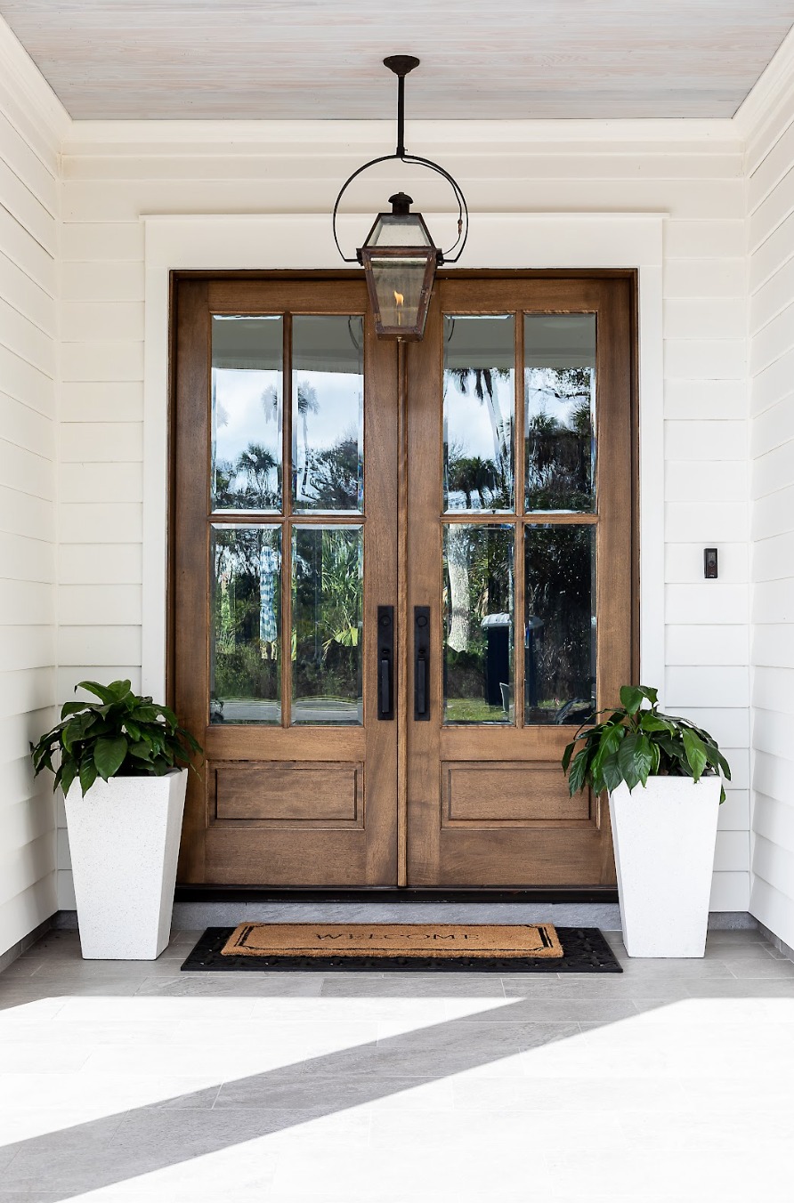Tall White Planters Flank Wood Doors with Greenery