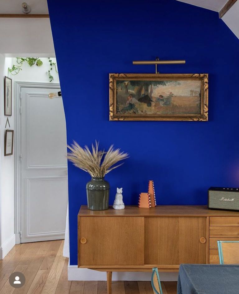 Gold Picture Light Highlights Artwork on a Cobalt Blue Wall