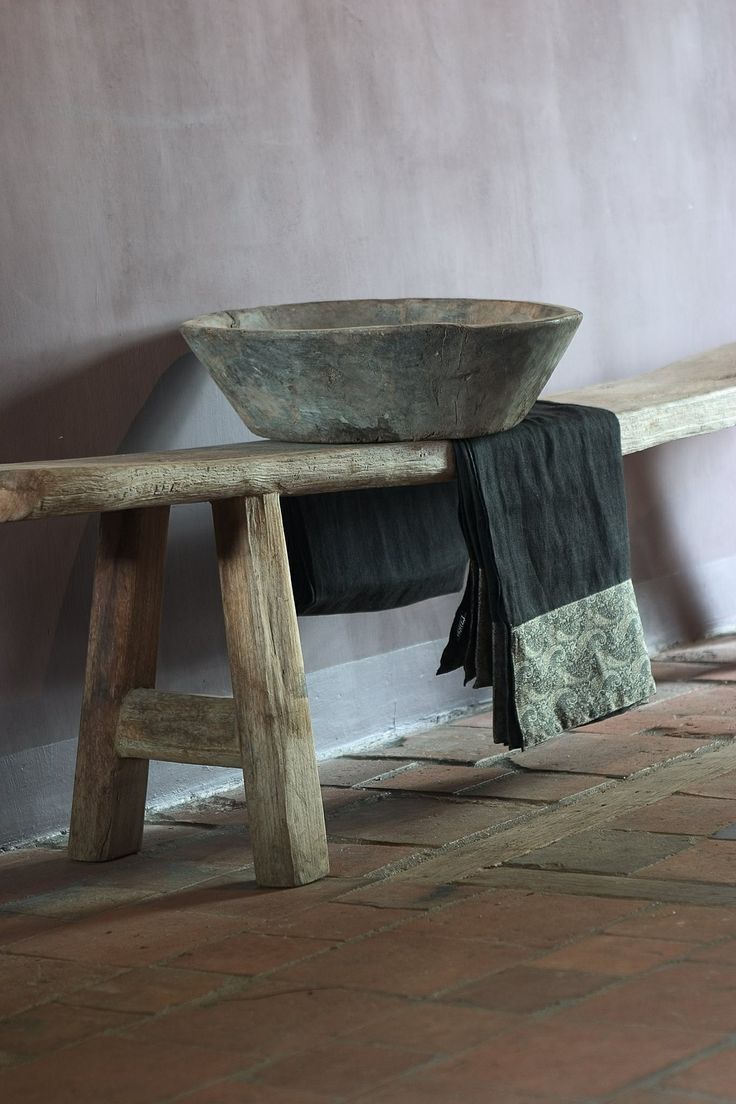 Ancient Wooden Bowl Holds Folded Textiles on a Rustic Bench