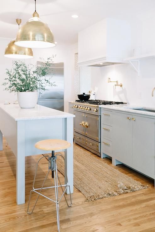 Brass Pendant Lights Over a Kitchen Island With a Plant