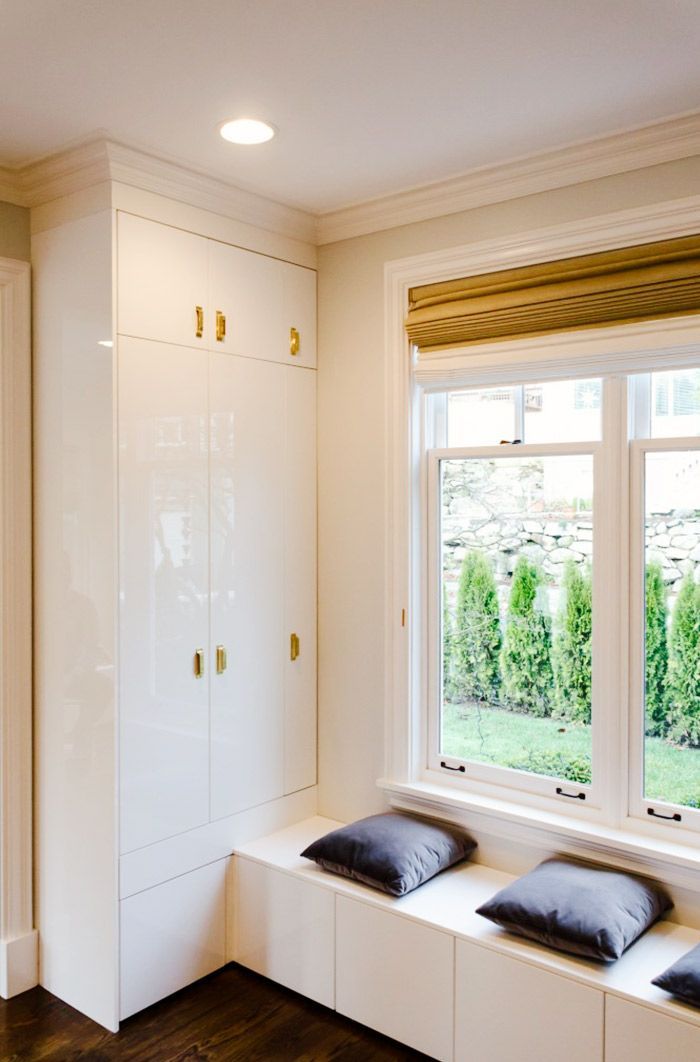 High-Gloss White Cabinets and Bench with Brass Pulls Add Refined Detail