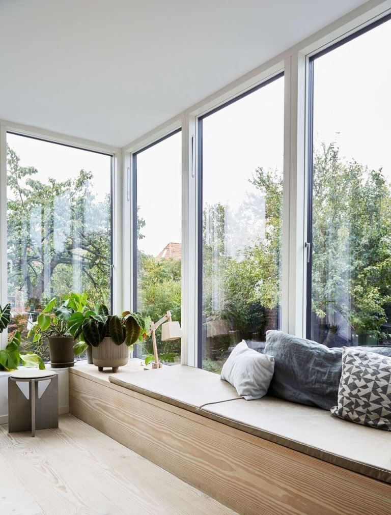 Light Wood Cabinet Under Large Windows Creates Cozy Seating and Storage